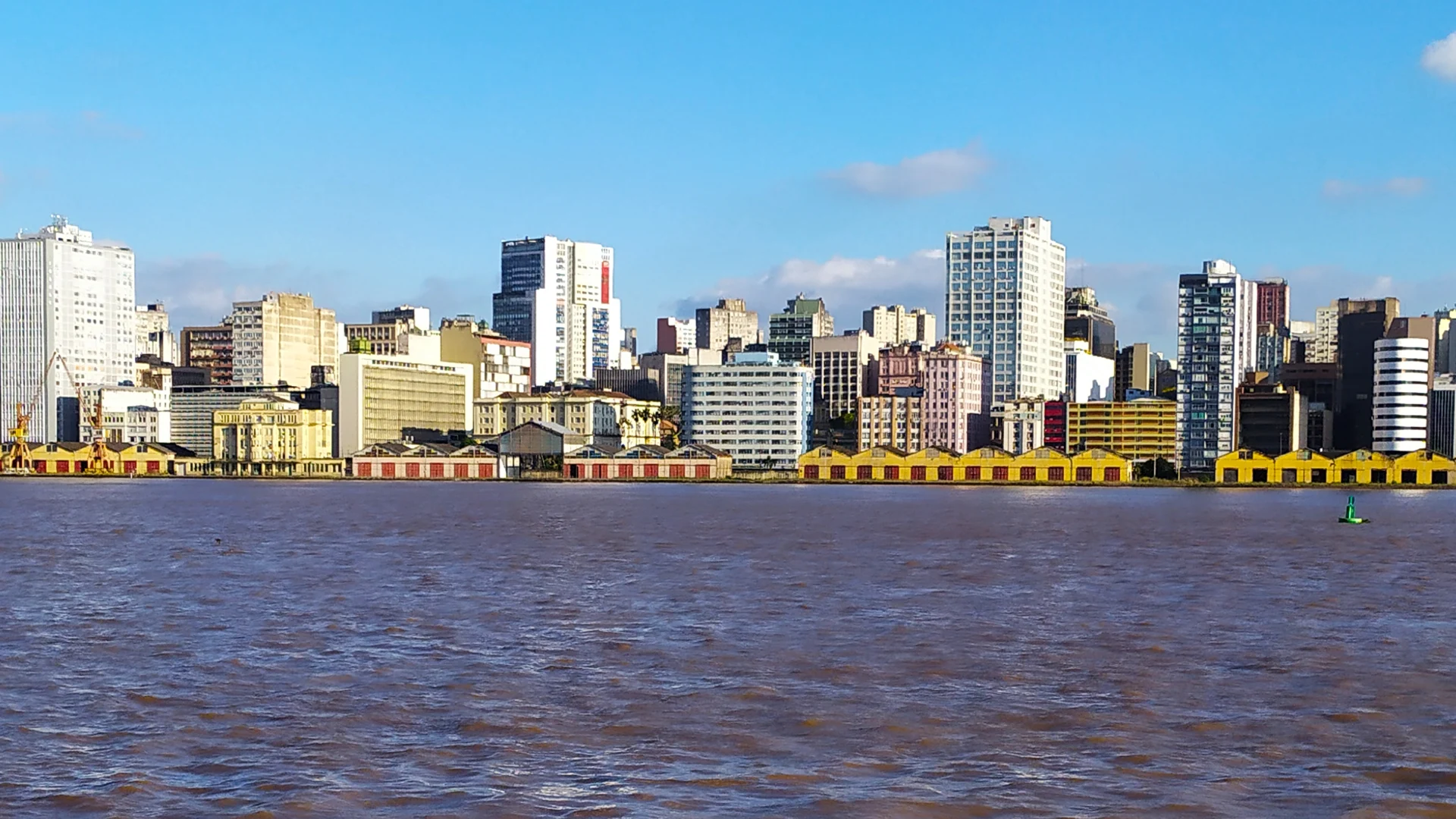 Vista de Porto Alegre a partir do Guaíba, com edifícios do Centro e armazéns do cais na orla.